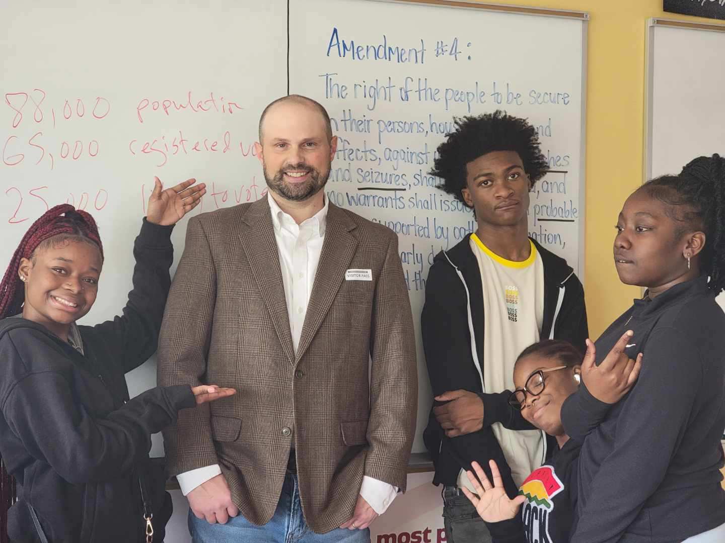 Robert stands, smiling, surrounded by high school students
